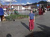 Tibet Lhasa 02 03 Peter Ryan in Barkhor Square with Jokhang behind As Peter Ryan waited for me to take photos of the Jokhang in the extremely hot 27C afternoon sun, he threw up for the first time in his life. His legs felt wobbly, his neck hurt, his stomach was upset and he turned pale. He thought he was going to burp, but the Sprite I forced him to drink at the Kyichu Hotel came up instead. Here he is standing at the historic spot three minutes later, at the edge of Barkhor (renamed Barfkhor) Square with the Jokhang behind. I think altitude sickness was responsible, and my forcing him to drink the can of sprite.